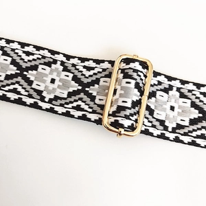 Detailed macro view of the black and grey geometric jacquard strap with gold metal buckle