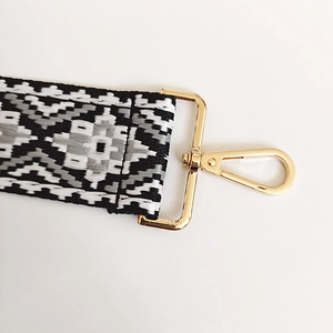 Close-up of geometric jacquard canvas bag strap with golden lobster clasp and weaving