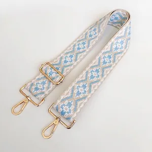 Close-up of ethnic style woven strap in sky blue and cream with gold metal swivel hooks