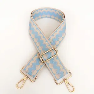 Detail of adjustable blue and beige woven strap with golden lobster clasps for bags