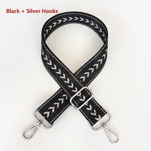 Close-up of black adjustable nylon shoulder strap with white arrow pattern and silver hooks
