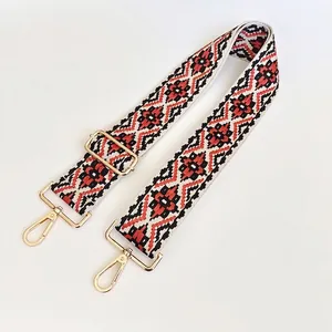 Detail of red and black ethnic woven bag strap with golden metal hooks and adjustable buckle