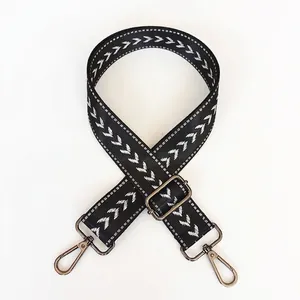Detail view of wide black nylon bag strap with white chevron pattern and gunmetal hardware