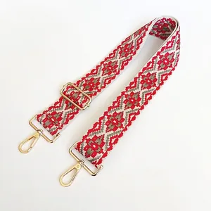 Detail of red geometric ethnic strap with gold metal hooks and white leather reinforce