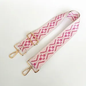 Detail of adjustable pink and white geometric rhombus woven canvas bag strap with gold hooks