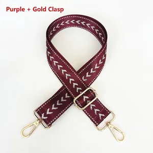 Close-up of wine red nylon strap with white arrow pattern and golden metal hooks