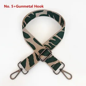 Detail view of the embroidered green and beige adjustable bag strap with dark metal hooks