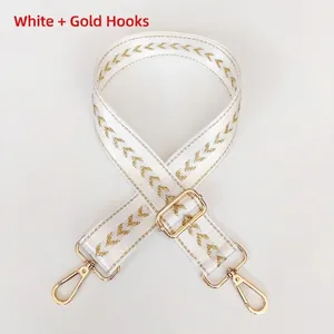Detail of white nylon shoulder strap with gold chevron weaving and metallic lobster clasps