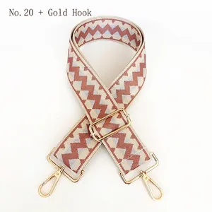 Detail view of woven geometric bag strap in brown and blue with gold metal hooks
