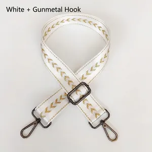 Detail of white nylon bag strap with gold V-pattern and gunmetal swivel snap hooks
