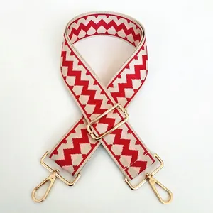 Detail view of ethnic wide bag strap with red and white zigzag weave and gold hooks