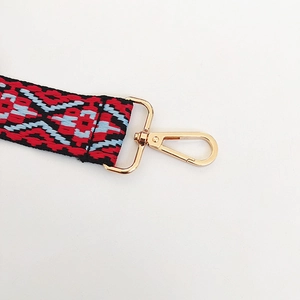 Close-up of bohemian canvas bag strap with red geometric patterns and gold metal clasps