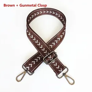 Detail view of brown nylon shoulder strap with white arrow patterns and gunmetal hooks