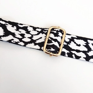 Detailed macro shot of leopard print bag strap with polished gold-tone metal buckle