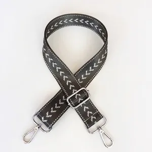 Close-up of adjustable grey nylon bag strap with white chevron pattern and silver hooks