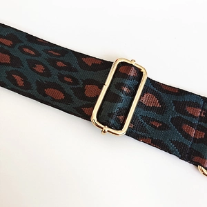 Close-up of leopard pattern nylon shoulder strap with gold adjustable metal buckle