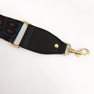 Detail of leopard print nylon strap with black leather ends and gold metal lobster clasps