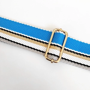 Detail of adjustable wide woven shoulder strap with blue stripes and gold metal buckle