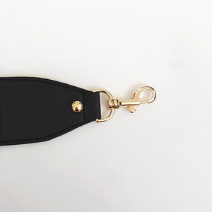 Close-up of golden swivel hooks and rivets on black adjustable canvas bag shoulder strap