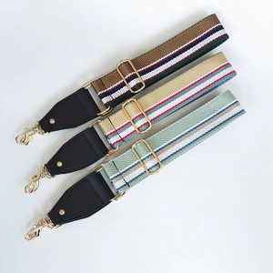 Close-up of adjustable striped canvas bag straps with gold metal hooks and hardware