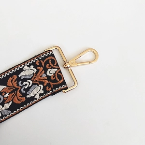 Detail of bohemian jacquard bag strap showing golden lobster clasp and floral pattern
