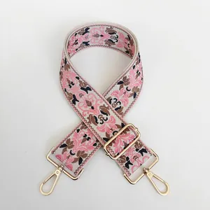 Detail view of ethnic embroidery pattern bag strap with gold metal hook and floral texture