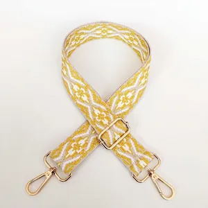 Detail of adjustable wide canvas shoulder strap with yellow geometric patterns and gold buckles