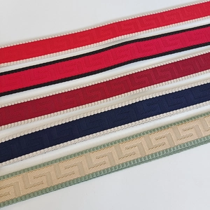 Dettaglio della tracolla regolabile con motivi greci colorati e bordi in tessuto a zigzag