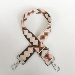 Detail of adjustable canvas bag strap with pink and brown geometric jacquard and silver hooks