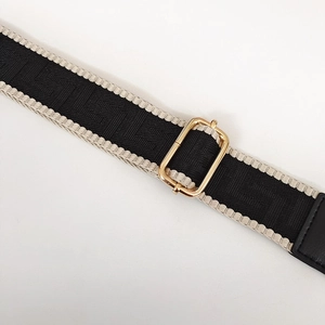 Dettaglio della tracolla regolabile con motivo jacquard bianco e nero e fibbia dorata