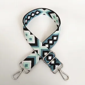Detail view of woven canvas bag strap with geometric jacquard pattern and silver metal hooks