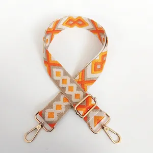 Detail of bohemian geometric orange canvas strap with golden lobster clasps and buckles