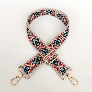 Close-up of ethnic geometric jacquard strap with golden rotating metal hooks and slide buckle