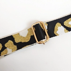 Close-up of leopard pattern strap with woven gold threads and adjustable gold buckle