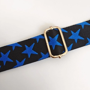 Detail of adjustable metal buckle and star pattern on nylon bag strap with gold hook