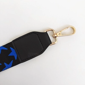 Detail of adjustable star pattern bag strap featuring a golden metal lobster clasp