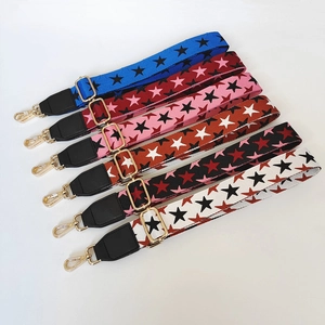 Detail of adjustable wide bag straps with star patterns and gold metal buckles