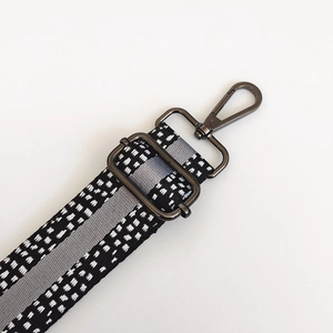 Close-up of adjustable spotted shoulder strap with grey stripe and gunmetal hardware