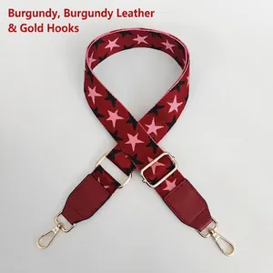 Detail view of adjustable burgundy strap with star pattern and golden swivel snap hooks