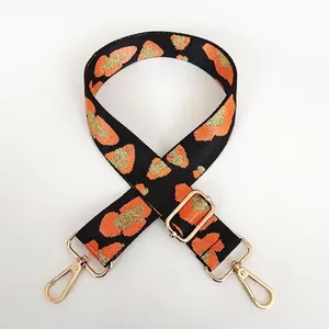 Detail of adjustable leopard print bag strap with orange pattern and gold metal hooks