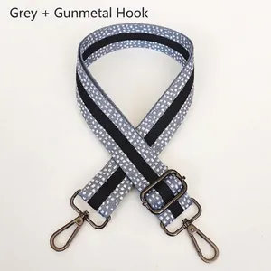 Detail view of grey patterned shoulder strap with gunmetal hooks and adjustable buckle