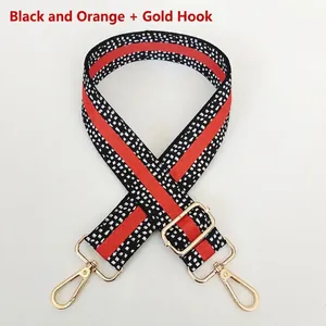 Detail of adjustable black and orange woven bag strap with white dots and gold hooks