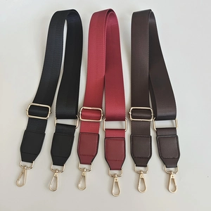 Close-up of adjustable nylon bag straps in black, burgundy, and dark brown with gold clips