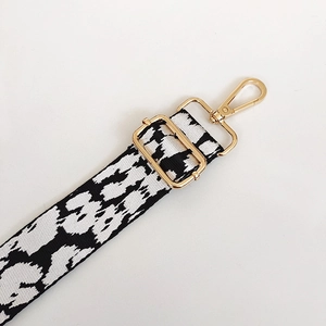 Detail of adjustable black and white animal print bag strap with polished gold hardware