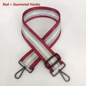 Close-up of adjustable striped woven bag strap with gunmetal swivel hooks and metallic thread