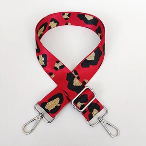 Detail of red leopard pattern crossbody bag strap with adjustable silver metal hardware