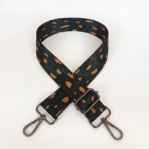 Détail d'une bandoulière léopard réglable avec crochets métalliques et texture tissée