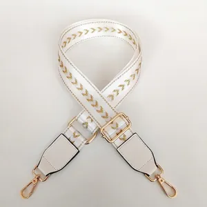 Adjustable wide white woven shoulder strap with gold metallic V-pattern and gold metal hooks