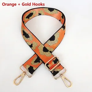 Detail of adjustable leopard print bag strap with orange webbing and gold metal clasps