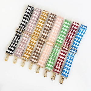 Detail of adjustable houndstooth patterned bag straps with gold metal hooks and buckles